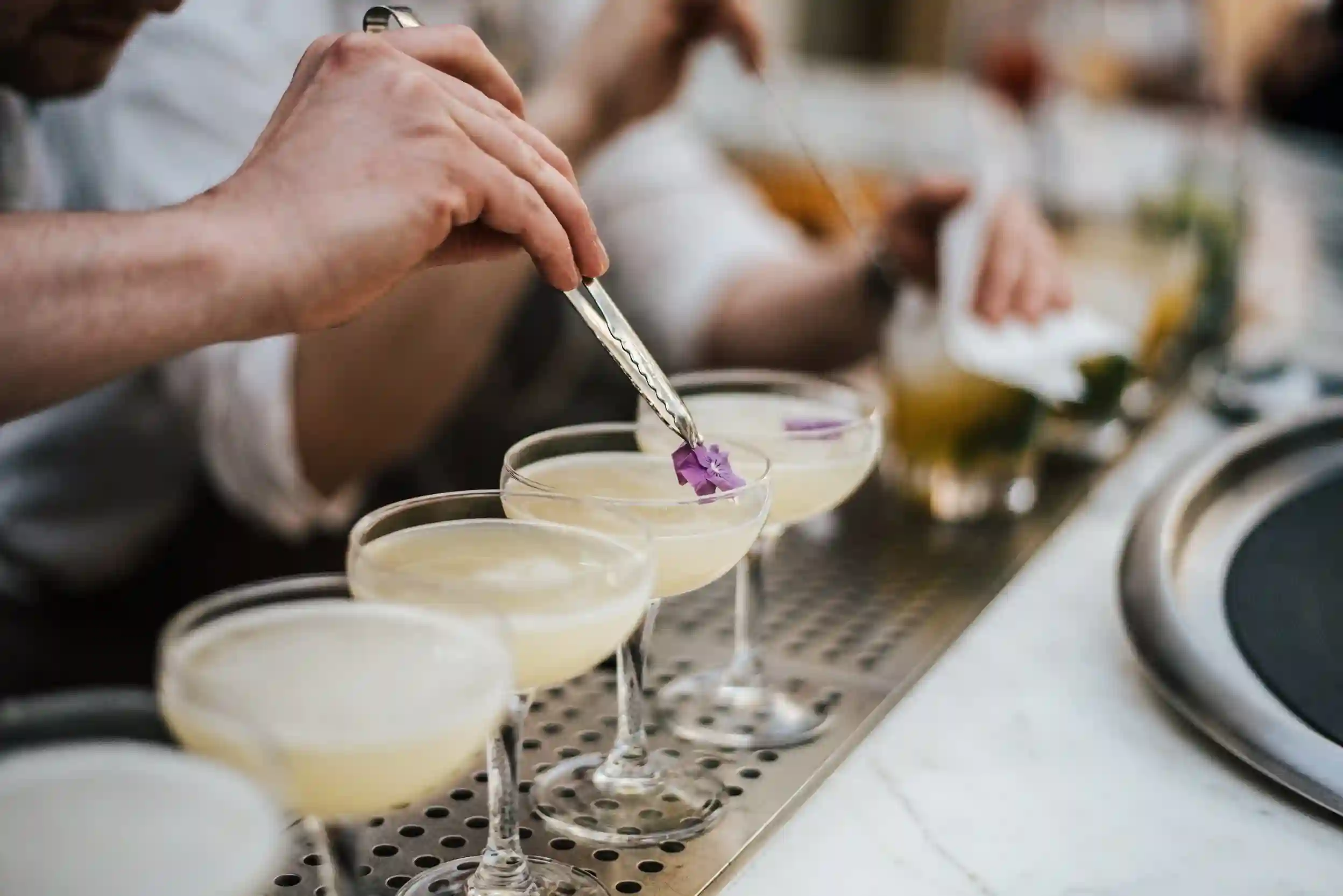 A closeup shot of a barman making margaritas with five glasses set in line